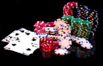 casino chips, red dice, and cards strewn upon a table representing online casino table games