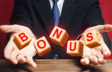 businessman with suit and tie tossing five cubes in the air with the word bonus spelled out in red letters.