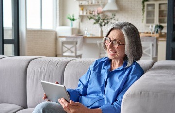 happy attractive older woman curled up on her sofa enjoying mobile casino gaming on her tablet 