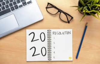2020 New Year's resolution list sitting on a desk with pencil and coffee