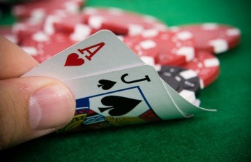 a man with a blackjack with an ace of hearts and a jack of spades. red casino chip are on the table.