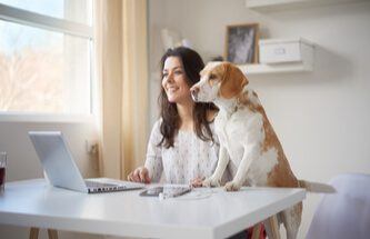 woman playing at Everygame Casino on her laptop with her dog looking on