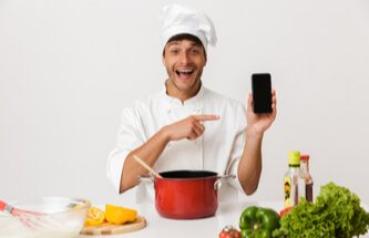 a chef cooking and playing Everygame Casino on his phone at the same time