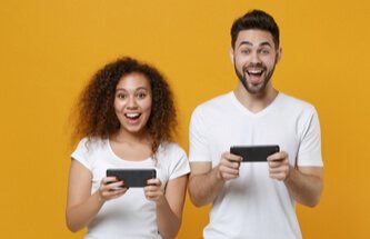 guy and girl each playing on their phone against a bright yellow background