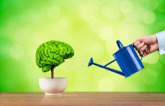 a miniature tree in a planter where the green of the tree is a brain and a hand watering the "tree" with a blue watering can