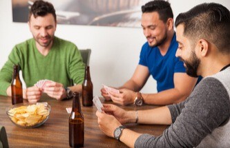 group of friends playing poker with beers and potato chips on the table