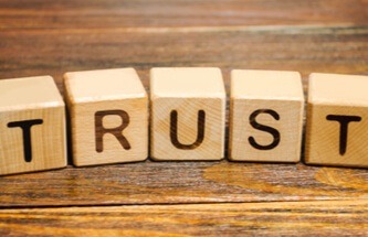 the word TRUST spelled out on 5 wooden blocks with one letter on each block