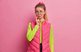 woman thinking deeply about her New Year's resolutions on a pink background