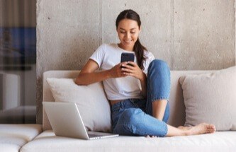 woman relaxing on her sofa playing at Everygame Casino on her phone