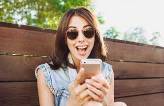 woman sitting in the park playing Everygame Casino games on her phone