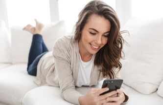 woman relaxing on her sofa playing Everygame Casino games on her phone