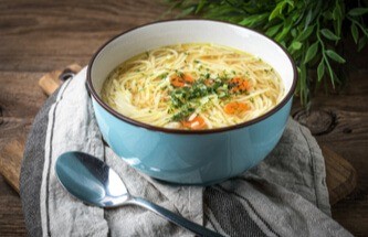 bowl of chicken noodle soup sitting on the table