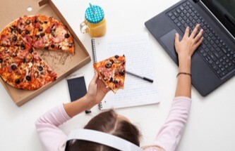 woman playing Everygame games on her laptop while eating pizza and drinking orange juice