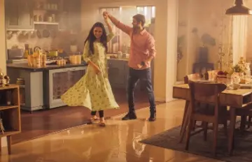 a young couple dancing in the kitchen with big smiles on their faces
