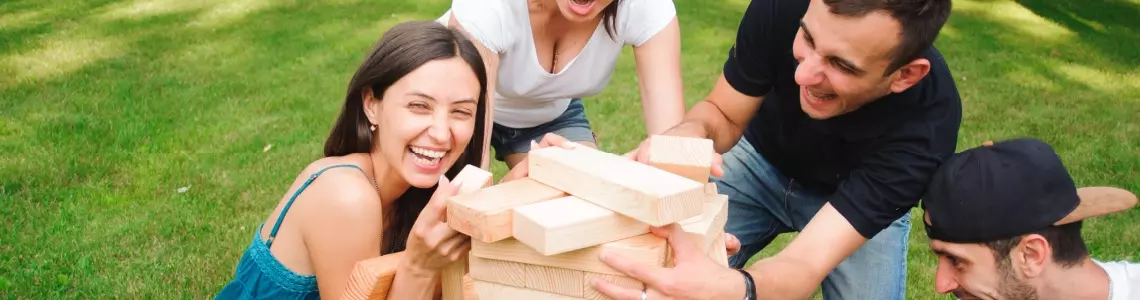 four friends, two women and two men, in their twenties or thirties playing Jango outdoors in a park with bricks