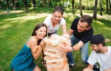 four friends, two women and two men, in their twenties or thirties playing Jango outdoors in a park with bricks
