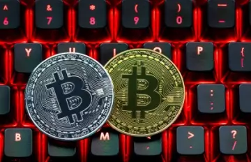 two bitcoins, one gold and one silver, placed on a computer keyboard to show that these currencies can be used as real money