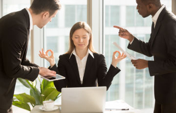 young businesswoman controlling her emotions through meditation in a stressful meeting with two male colleagues