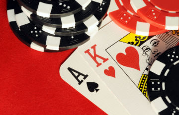 Ace of spades and king of hearts lying on poker table with chips all around