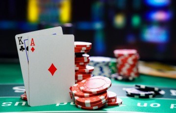 a hand with blackjack over a green felt table with red, black, white, and green casino chips on the table 