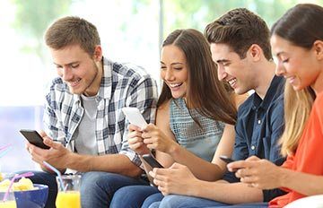 a group of four young adults playing games on their mobile phones