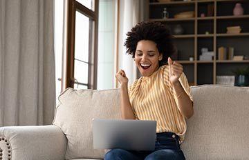 happy woman playing online casino games while sitting on her sofa