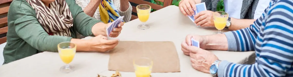 Two happy and smiling senior citizen couples enjoying a card game together