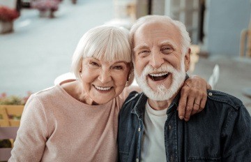 a white haired older couple showing great joy. He has a short white beard and she looks as pretty as she did when she was 25.