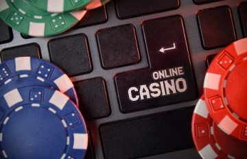 A section of keyboard with words online casino on a key with blue, red, and green casino chips on the keyboard