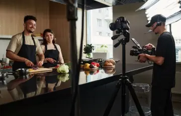 a smiling young couple making a cooking show together that people will watch for entertainment