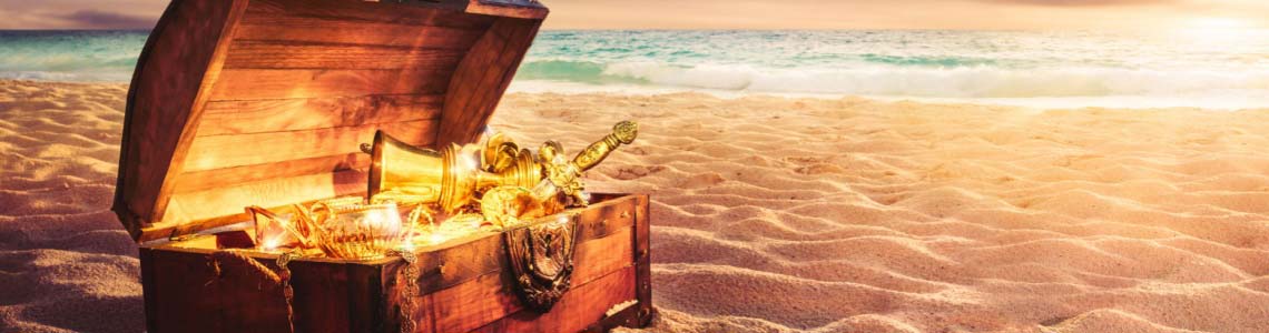 a treasure chest on a beach with the sun reflecting brightly off of the golden objects inside