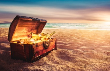 a treasure chest on a beach with the sun reflecting brightly off of the golden objects inside