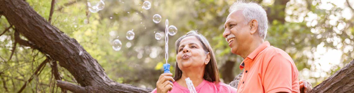 a white-haired older couple blowing bubbles in the park