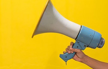 a hand held megaphone symbolizing marketing promotions on a bright yellow background