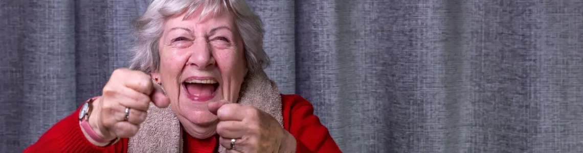 Older woman accepting a challenge with clenched fists and a huge smile on her face