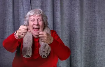 Older woman accepting a challenge with clenched fists and a huge smile on her face.