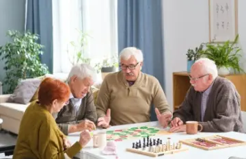 four older people enjoying playing a table game