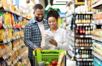 a young couple smiling as they shop together at a supermarket