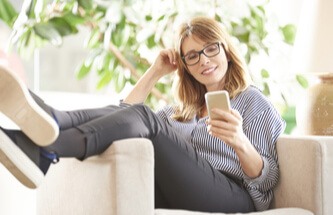 woman lounging on an easy chair looking at her phone