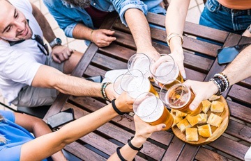 several friends celebrating the social return to normal by clicking their beer glasses together