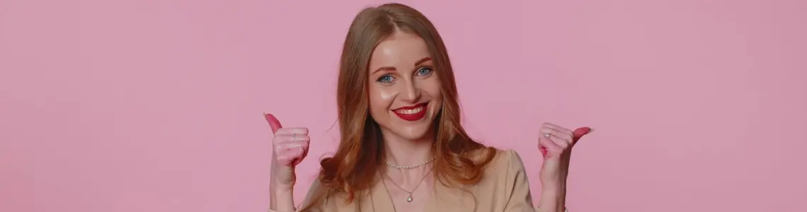 an attractive young woman with a big smile on her face and thumbs up signifying that she is in a very good mood
