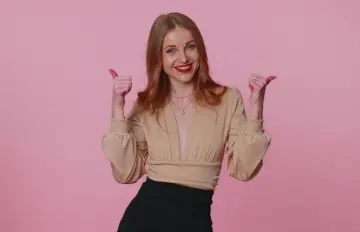 an attractive young woman with a big smile on her face and thumbs up signifying that she is in a very good mood