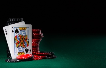 a blackjack with ace and king of spades.  the cards are leaning against black and red casino chips.