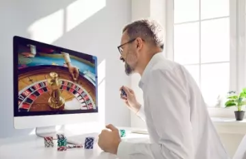 a young man with a short beard playing roulette online on a very large screen