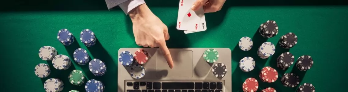 overhead view of man in suit playing at an online casino on his laptop with casino chips on the table