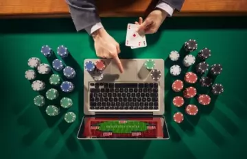 overhead view of man in suit playing at an online casino on his laptop with casino chips on the table