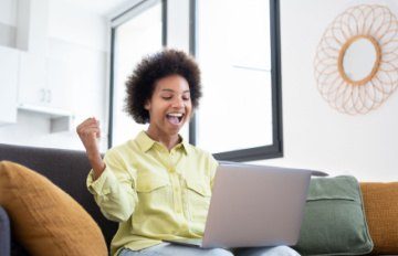 attractive young black woman enjoying online casino games comfortably on her sofa