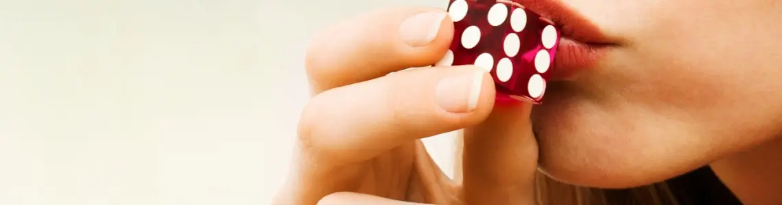 a very pretty woman kissing a red die before rolling the dice in craps