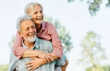 an older couple having fun with the man carrying the woman on his back