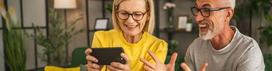 an elderly couple enjoying playing a game together on her phone